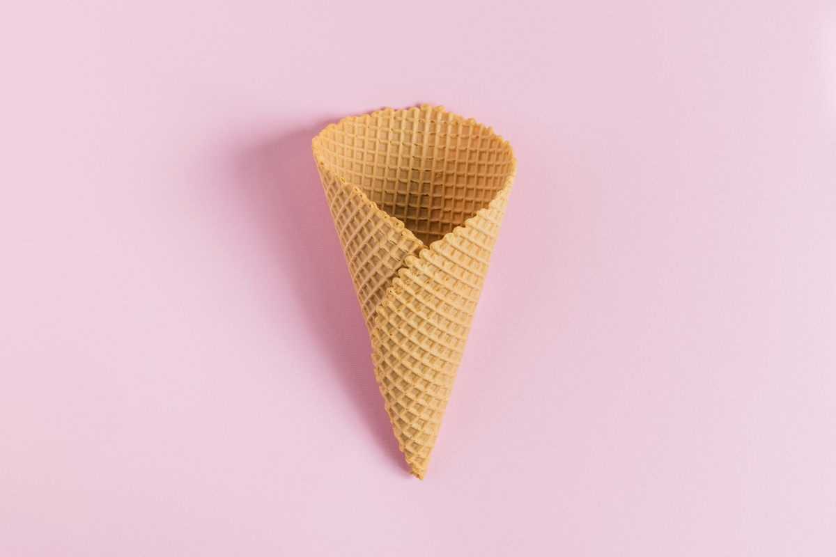 Empty big ice cream cone on light pink pastel background.